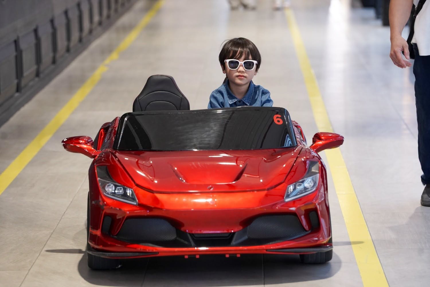 child in red electric toy car